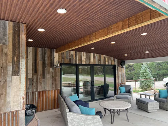 Covered patio with reclaimed-wood walls, a wood ceiling, and lounge furniture