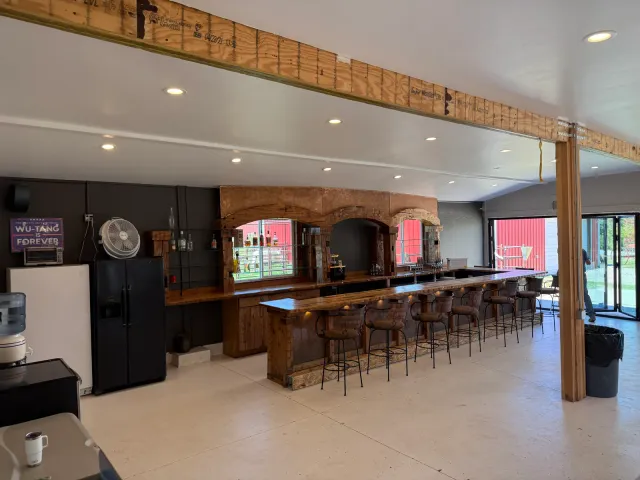 Remodeled open room with a long bar, stools, and timber posts and beams