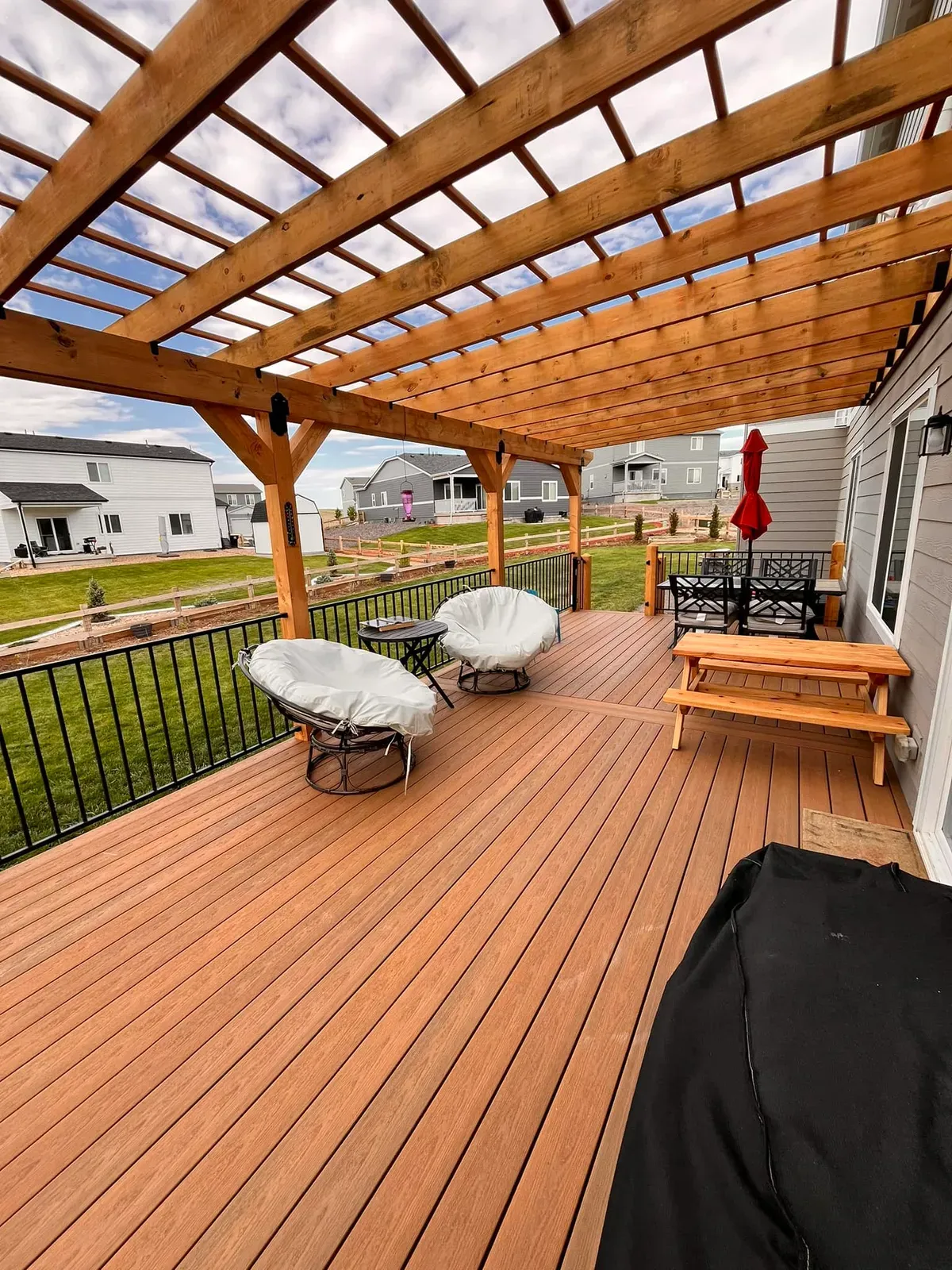 Composite deck under a cedar pergola with seating and a picnic table