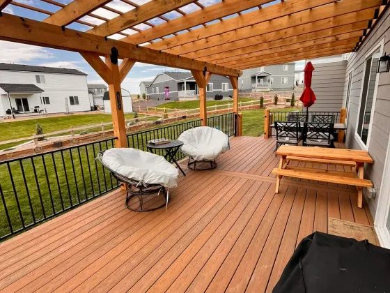 Composite deck under a cedar pergola with seating and a picnic table