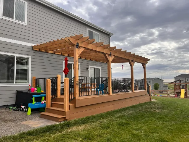 Side view of the pergola-covered deck with steps down to the yard