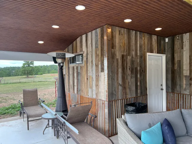 Covered patio with a reclaimed-wood accent wall, recessed lights, and outdoor seating