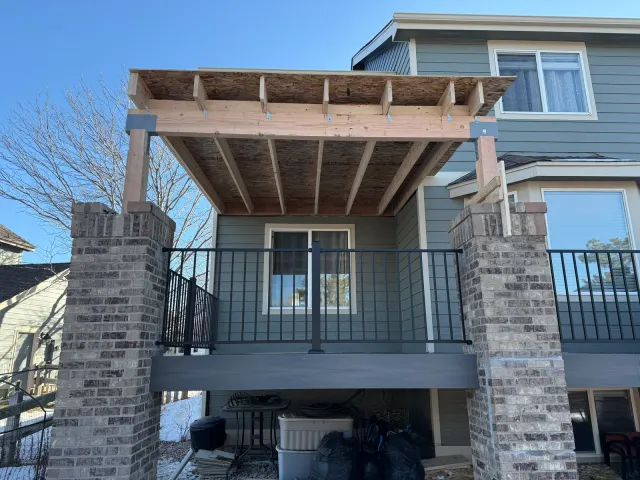 Pergola-style cover over an elevated deck between brick columns