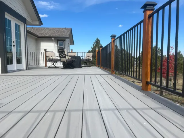 Gray composite deck with black metal balusters and stained wood posts