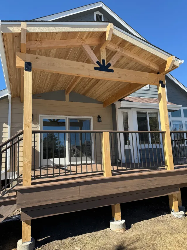 Gabled timber patio cover over a raised deck with black metal railing