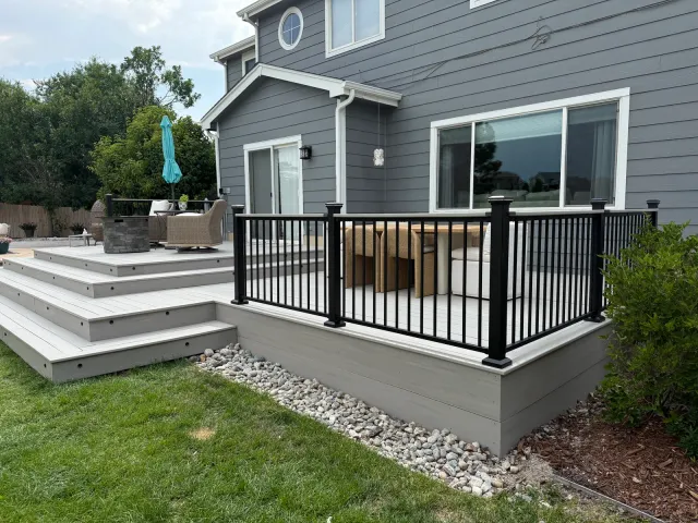 Gray composite deck with wide wraparound steps and black metal railing