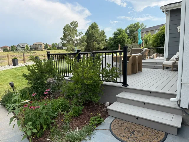 Composite deck steps leading down beside a flower garden