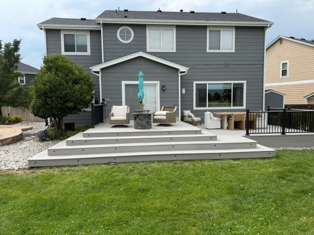 Rear of a two-story home with a wide, low composite deck and wraparound steps