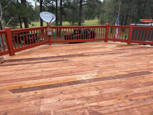 Newly built wood deck with red-painted railing among pine trees