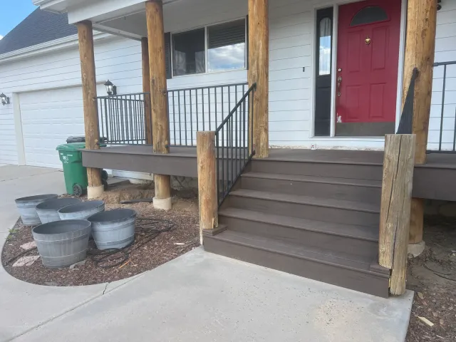 Front porch steps with log posts and black metal railing