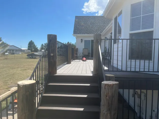 Deck stairs flanked by log posts with black metal railing