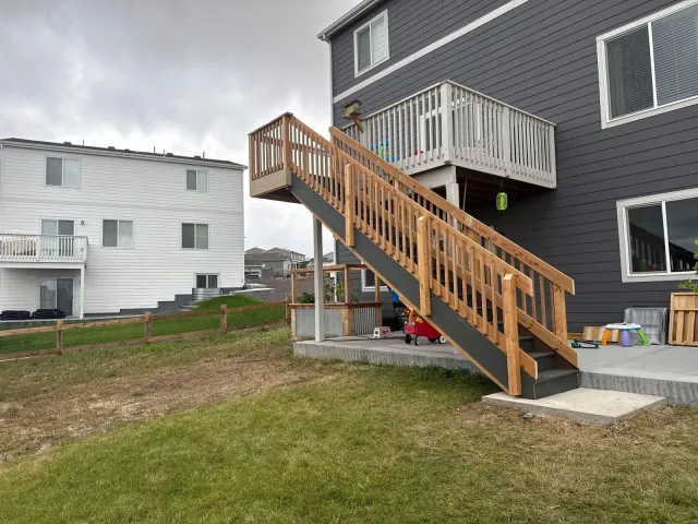 Wood stair and railing from a second-story deck down to the patio