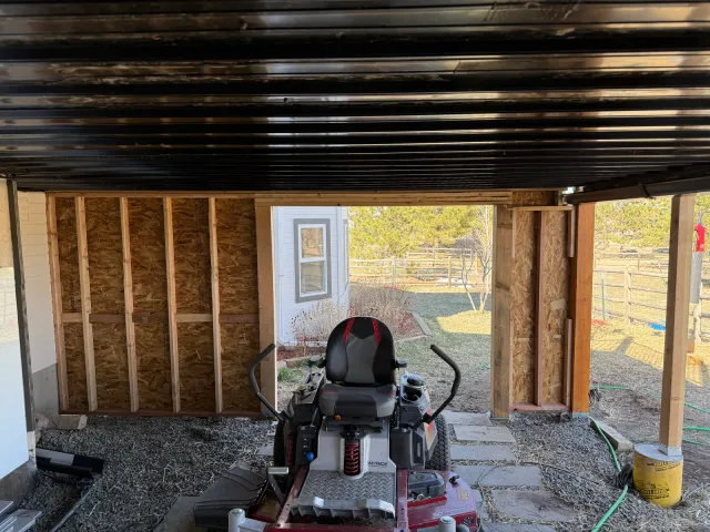 Framed under-deck storage enclosure with a riding mower inside, during construction