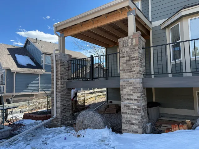 Covered deck with a timber-framed roof supported by brick columns