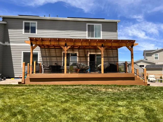 Stained wood pergola over a full-width backyard deck