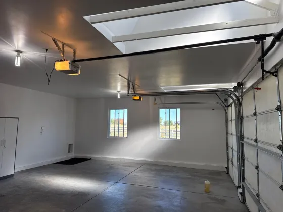 Finished garage with white painted walls, skylights, and garage door openers