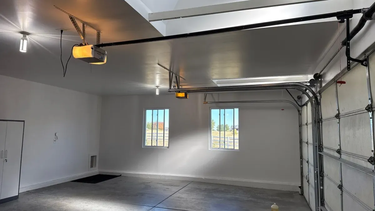 Finished garage with white painted walls, skylights, and garage door openers