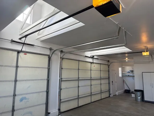 Finished garage with insulated garage doors and drywalled skylight wells