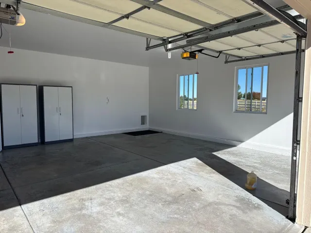 Sunlit finished garage with white walls and storage cabinets