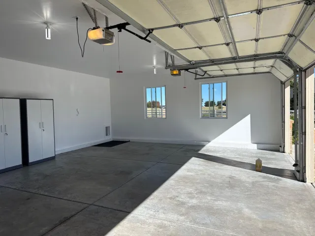Wide finished garage with painted walls and storage cabinets
