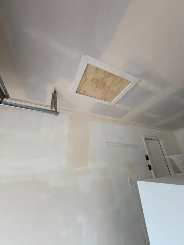Garage ceiling drywall taped and mudded around an attic access hatch