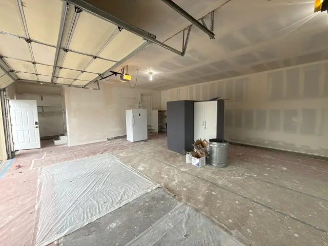 Garage interior after drywall finishing, with the floor covered for painting