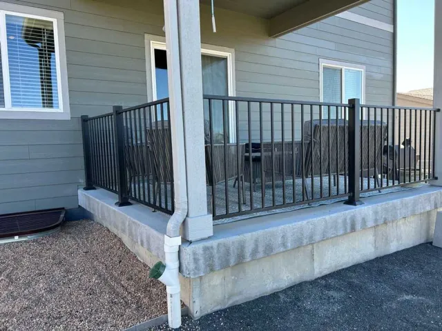 Black metal railing installed on a raised concrete porch