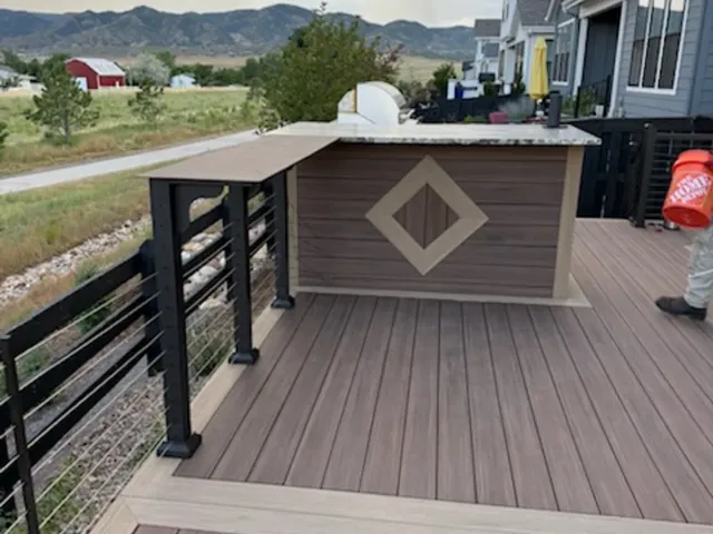 Finished composite bar wall with a diamond inlay and black metal railing, foothills behind