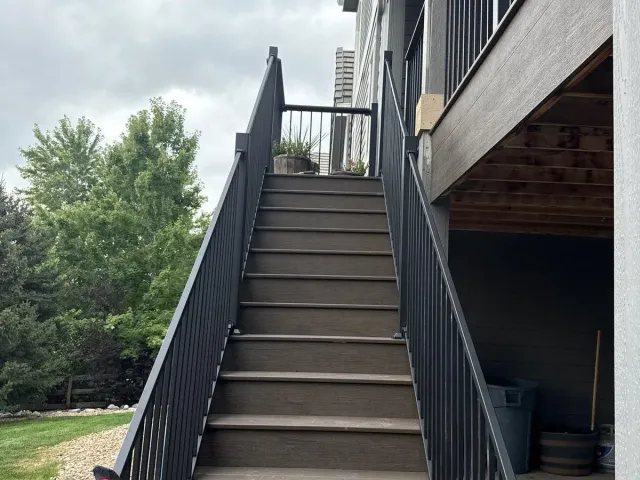 Composite stairs with black metal railing leading up to the deck