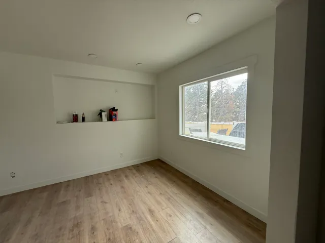 Finished basement bedroom with a built-in wall niche and wood-look flooring