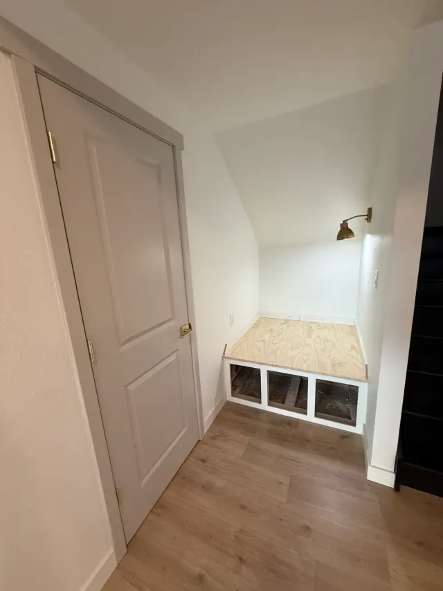 Under-stair nook with built-in bench storage and a wall sconce