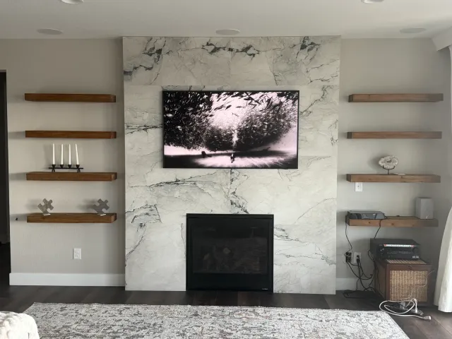 Marble-look fireplace surround with floating wood shelves on both sides