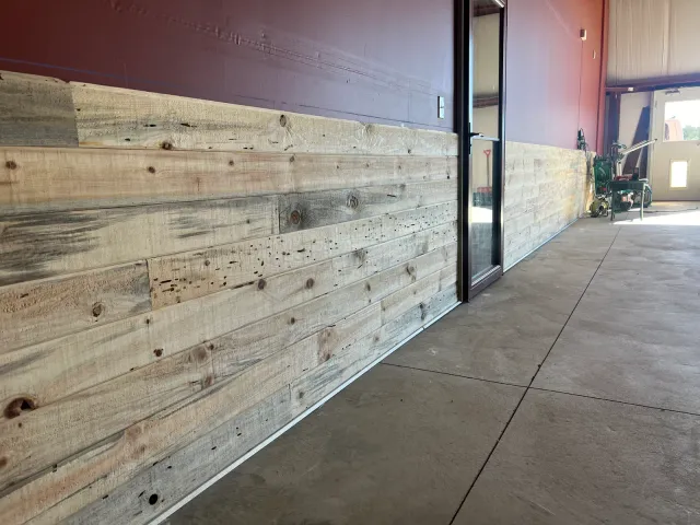 Rustic wood plank wainscot along a wall in a large shop space