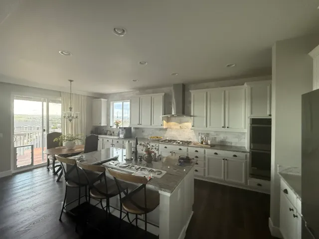 Kitchen with white cabinets, a large stone-top island, and bar seating