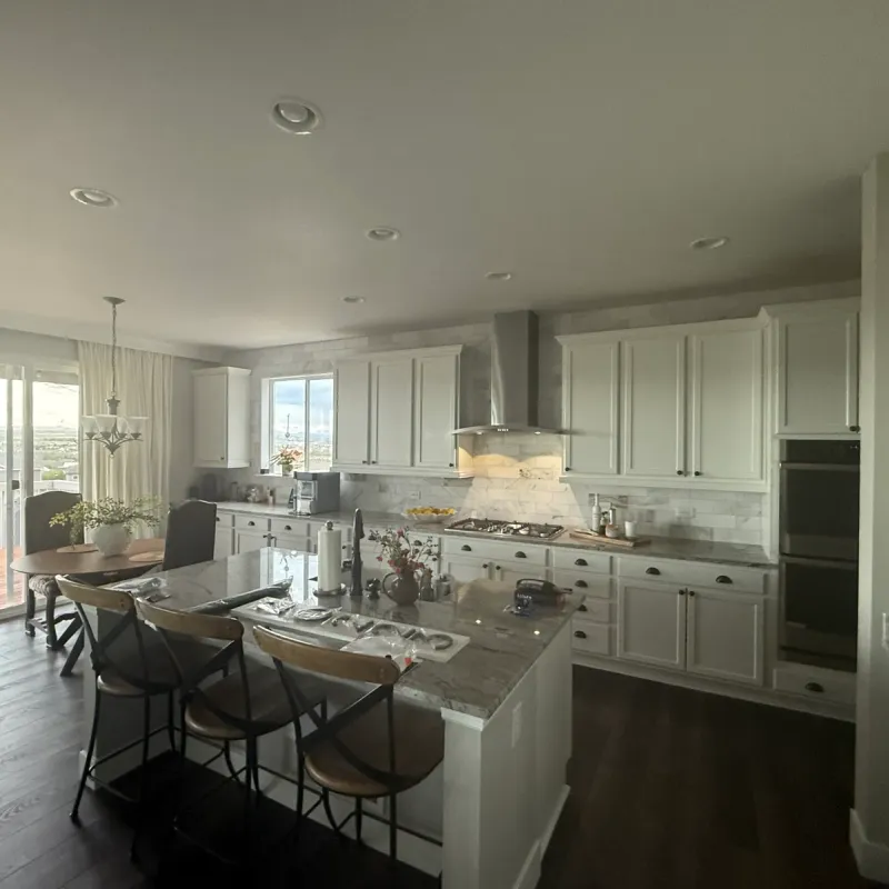Kitchen with white cabinets, a large stone-top island, and bar seating