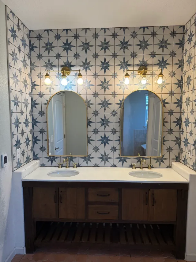 Double vanity with arched mirrors against blue star-pattern tile