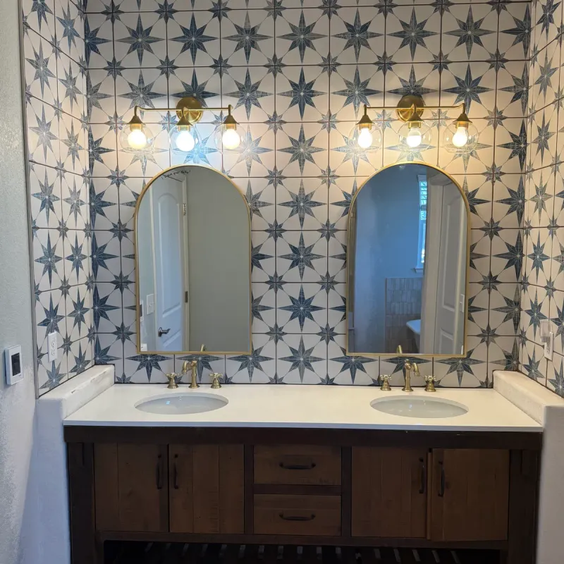 Double vanity with arched mirrors against blue star-pattern tile